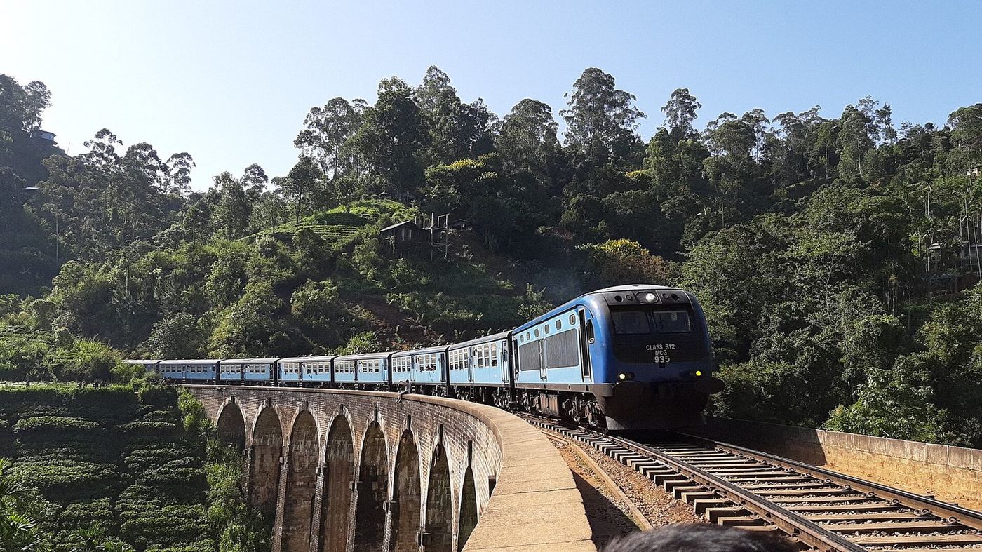 A blue train crossing Nine Arch Bridge near Ella